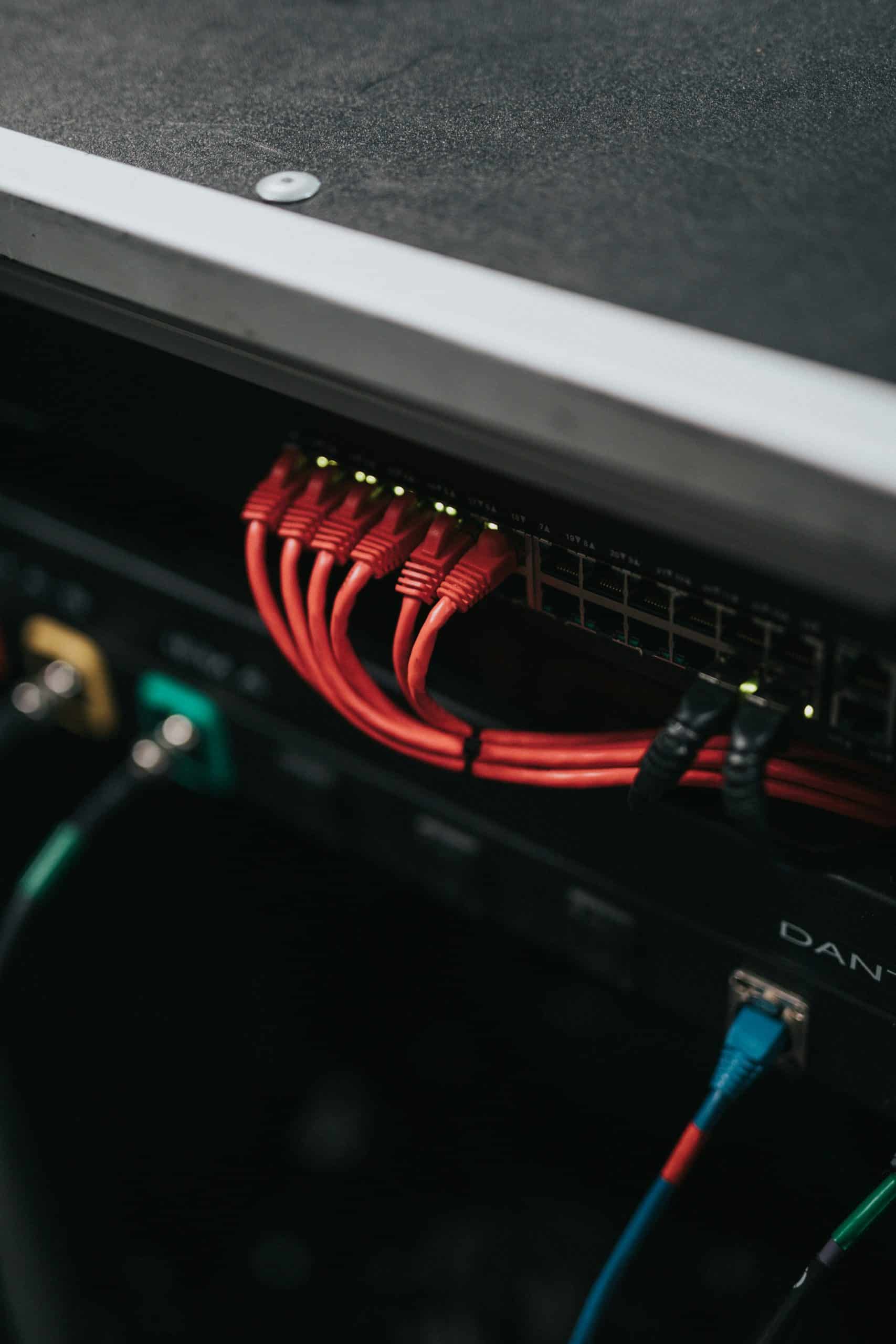 A close-up view of a network switch with multiple red Ethernet cables, along with a few black and blue cables, all organized in a server rack highlights secure networking in action.